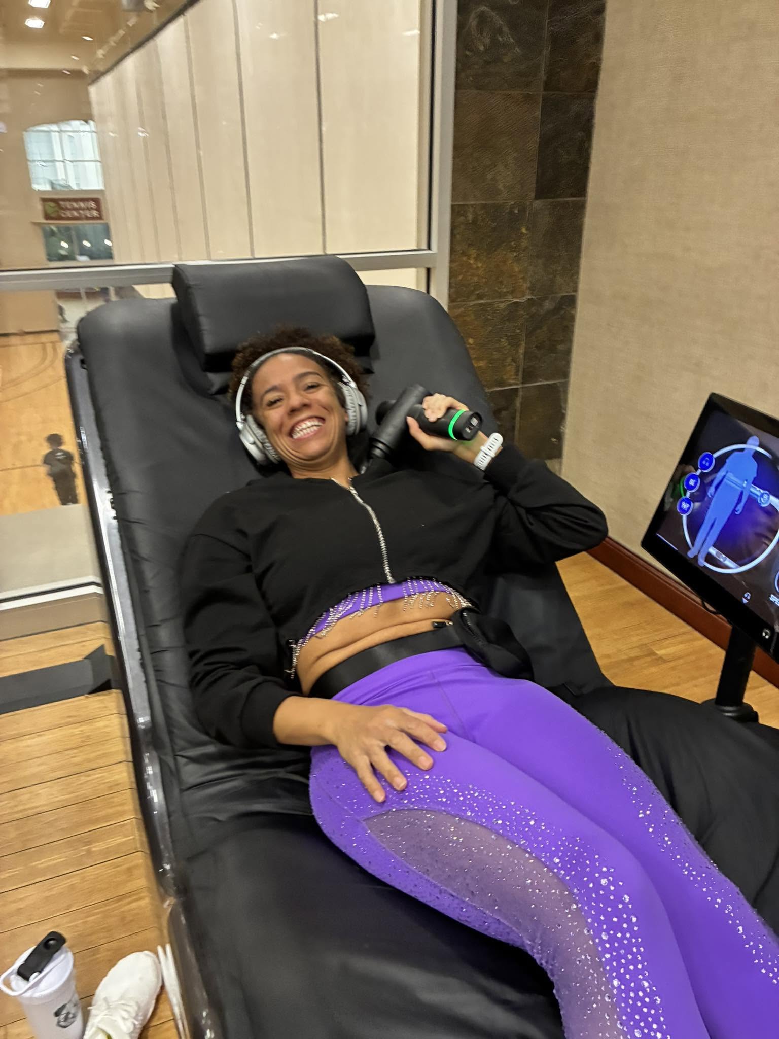 Theresa relaxing on a recovery chair at the gym with headphones